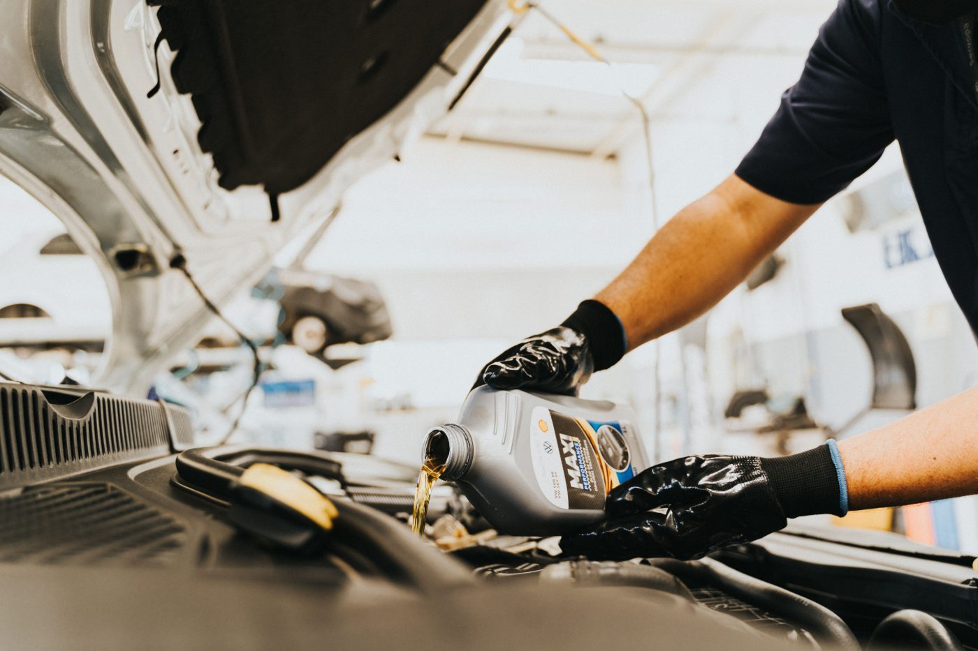 Maintenance in the workshop: a mechanic tops up fresh engine oil during an oil change